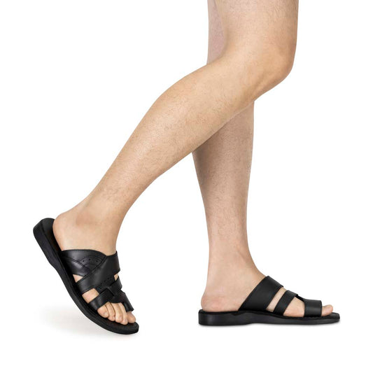 Model wearing Aron black, handmade leather slide sandals with toe loop - side view